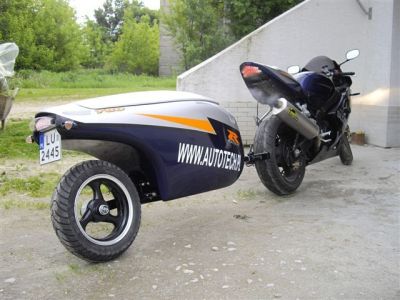 Sport motorcycle towing an aerodynamic single-wheel monowheel cargo trailer—compact luggage solution for motorcycle touring.