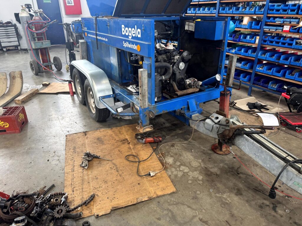 Bagela Spillwinde/Kabelziehwinde auf Trailer in der Werkstatt – geöffnete Haube mit sichtbar eingebautem Motor, Deichsel und Stützfuß; Wartung/Reparatur der Kabelzuganlage.
Anhänger reparatur und service von Dollco.