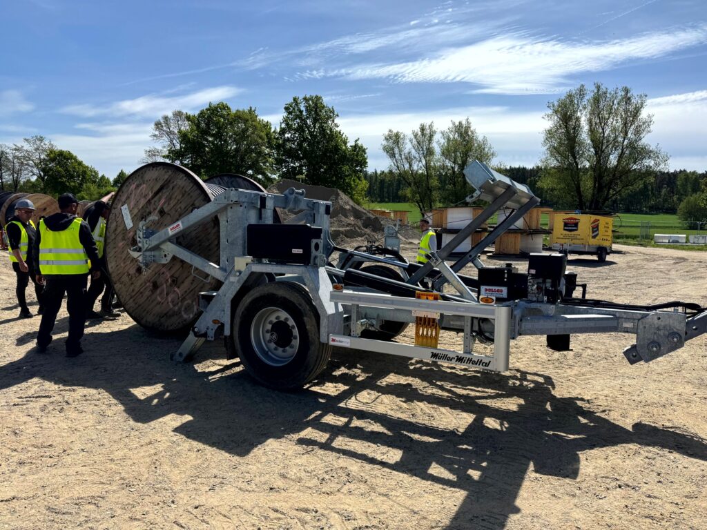 Hydraulisch absenkbarer Kabeltrommelanhänger auf Baustelle – verzinktes Fahrgestell mit Trommelaufnahme und Deichsel, ideal für Kabelverlegung im Leitungsbau/Glasfaser. Anhänger reparatur und service von Dollco.