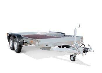 Tandem-axle transport flatbed trailer — galvanized frame with low loading deck, fold-down side boards, overrun brake and jockey wheel; ideal for moving machinery, vehicles and materials.